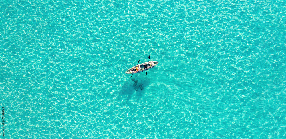 Summer vacation fun, sport activity. Men on Canoe kayak in turquoise blue Aegean Sea, aerial view.