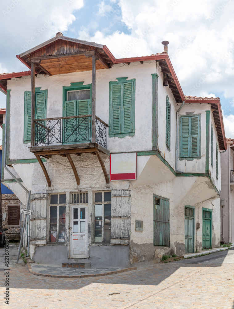 Greece, Arnaia Chalkidiki. Facade of aged two floor building, home and store, covered balcony.