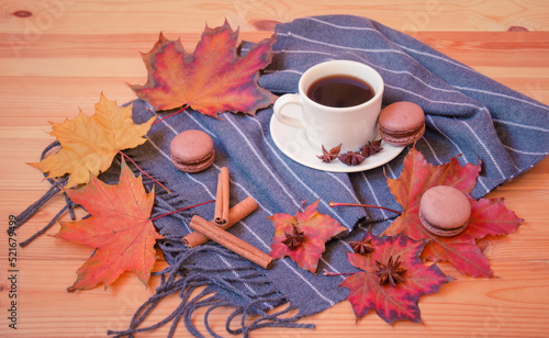 Coffee, scarf, chocolate macaroons, spices and autumn leaves on wood. Selective focus.
