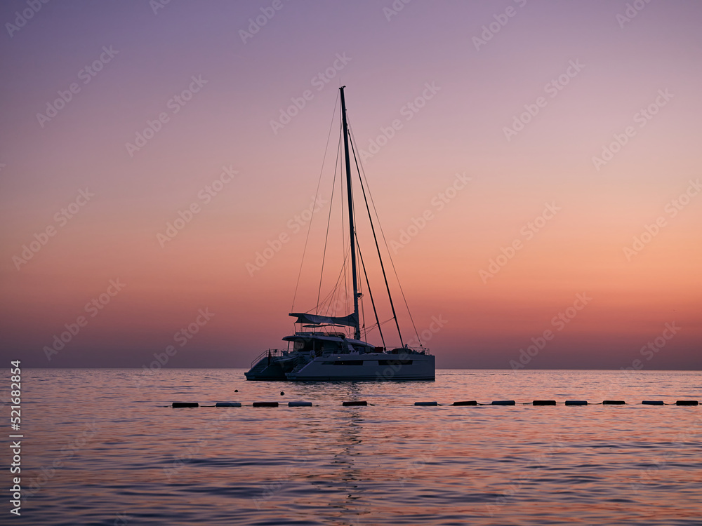 Catamaran moored in the Adriatic Sea after sunset. Beautiful sea landscape.