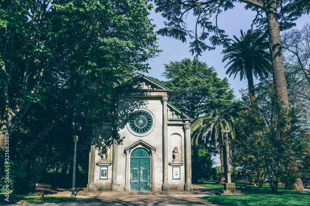 Small church with statues and palm tree in park 