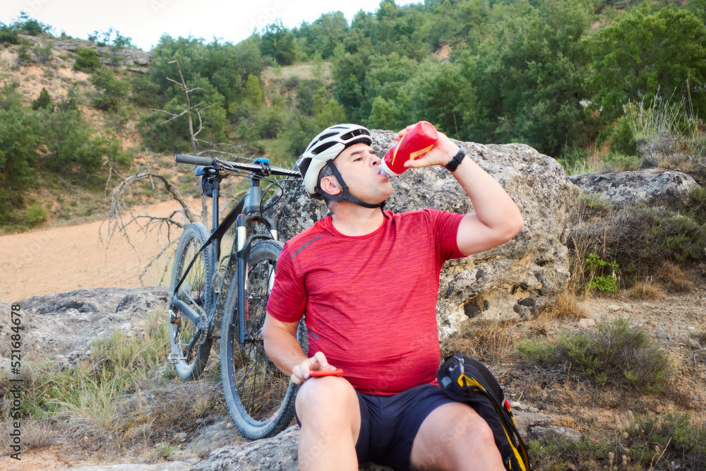 Naklejka premium a male cyclist drinking water, hydration during sport