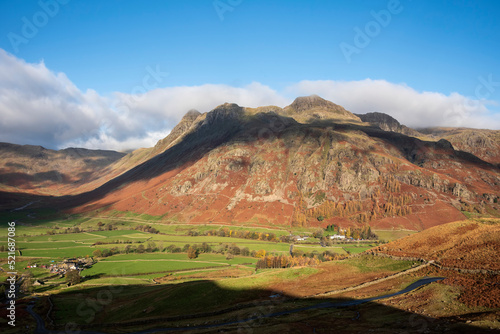 Colorful vibrant Autumn landscape image looking from Pike O'Blisco towards Langdale Pikes and Range with beautiful sungiht on mountains and valley