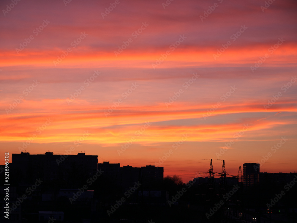 Bright sunset sky over the silhouette of the evening city. Beautiful bright sunset sky over building silhouettes