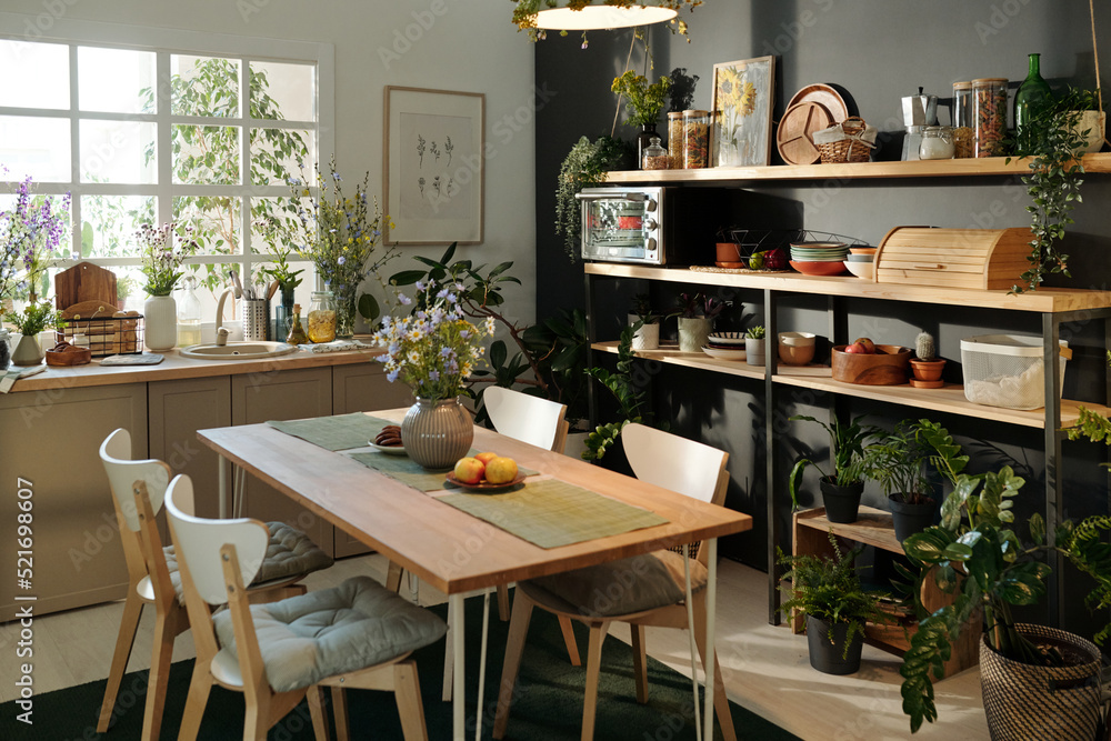Part of spacious cozy kitchen with sustainable table, kitchenware and house plants creating atmosphere of recharge and relax