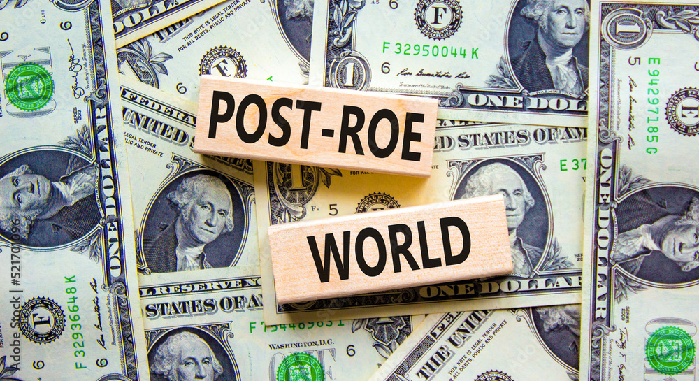 Roe vs Wade post-Roe world symbol. Concept words Post-Roe world on wooden blocks on a beautiful background from dollar bills. Business and Roe vs Wade post-Roe world concept. Copy space.