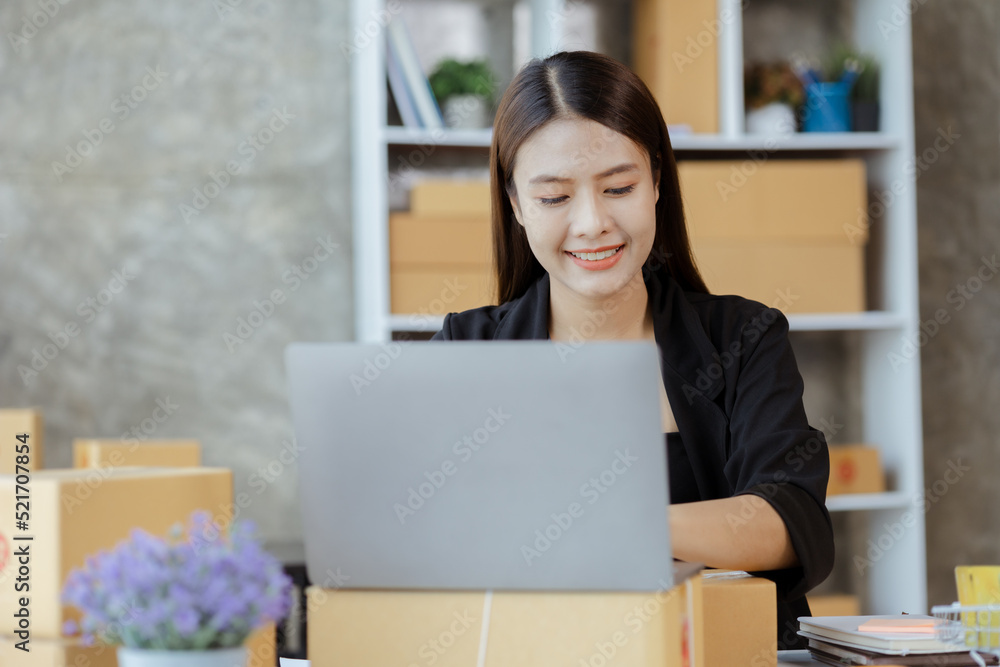 A beautiful Asian business owner opens an online store, she is checking orders from customers, sending goods through a courier company, concept of a woman opening an online business. A beautiful Asian business owner opens an online store, she is checking orders from customers, sending goods through a courier company, concept of a woman opening an online business.