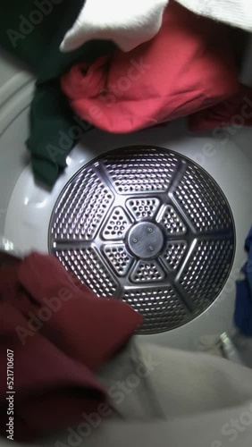 Slow motion vertical video of clothes tumbling in laundry dryer.