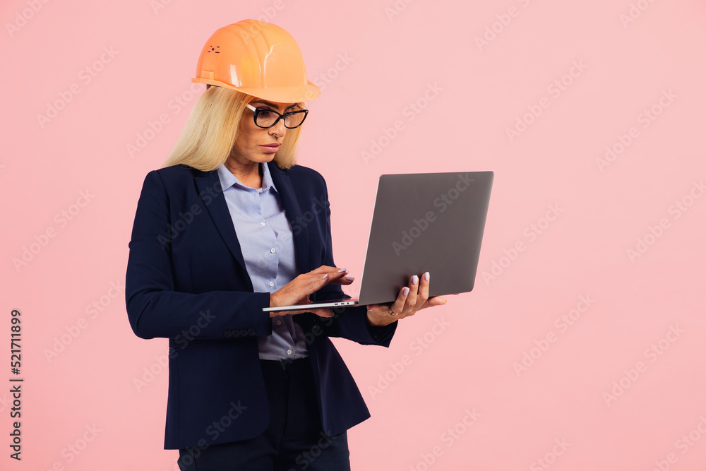 Architect or engineer woman in glasses use laptop on the pink background Architect or engineer woman in glasses use laptop on the pink background