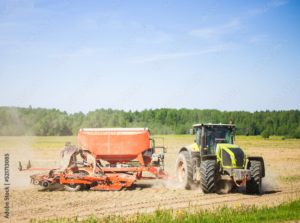 Fototapeta premium Collective farmers sow, sow crops in the field. big tractor working in the field, harvesting, doing business, farming. soil preparation for planting