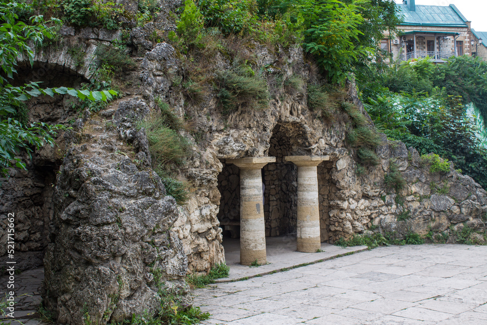 landmark in a famous place - diana's grotto with stone columns among green plants in the historical center of the city close-up in Pyatigorsk Russia