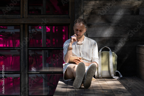 Valokuva Young man student wearing white shirt sits on wooden stairs step by bag outdoors