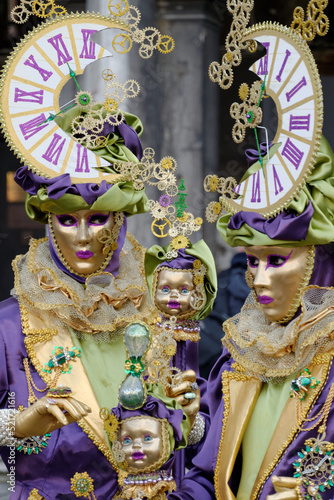 Venise, Italie - 27 février 2014 : Carnaval de venise, deux personnes deguisées en violet et or, et portant un chapeau composé d'une moitié d'horloge en forme de lune photo