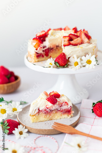 Strawberry vanilla cake on a white cake stand, with wooden forks and strawberries 