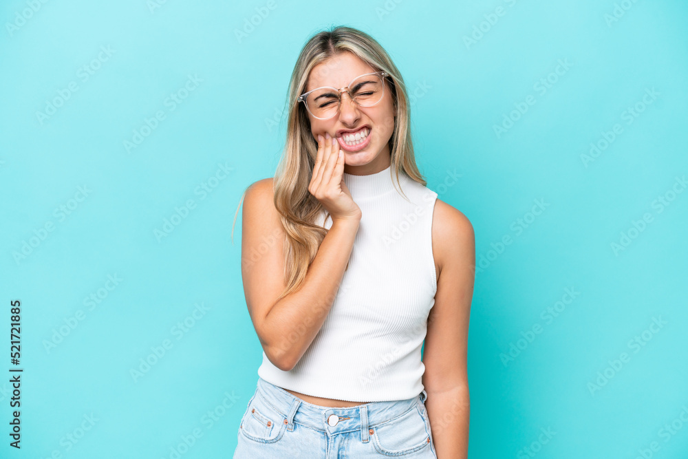 Young caucasian woman isolated on blue background with toothache Young caucasian woman isolated on blue background with toothache