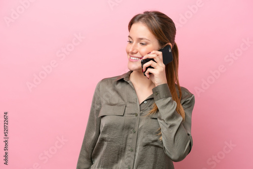 Young caucasian woman isolated on pink background keeping a conversation with the mobile phone with someone