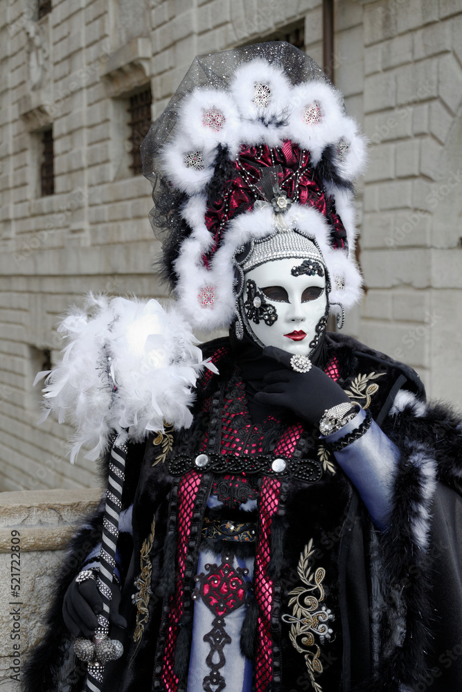 Venise, Italie, 27 février 2014 : carnaval de Venise, femme déguisée en noir, rouge et avec des plumes blanches