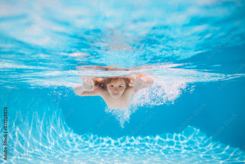 Child swimming underwater in swimming pool. Funny kids boy play and