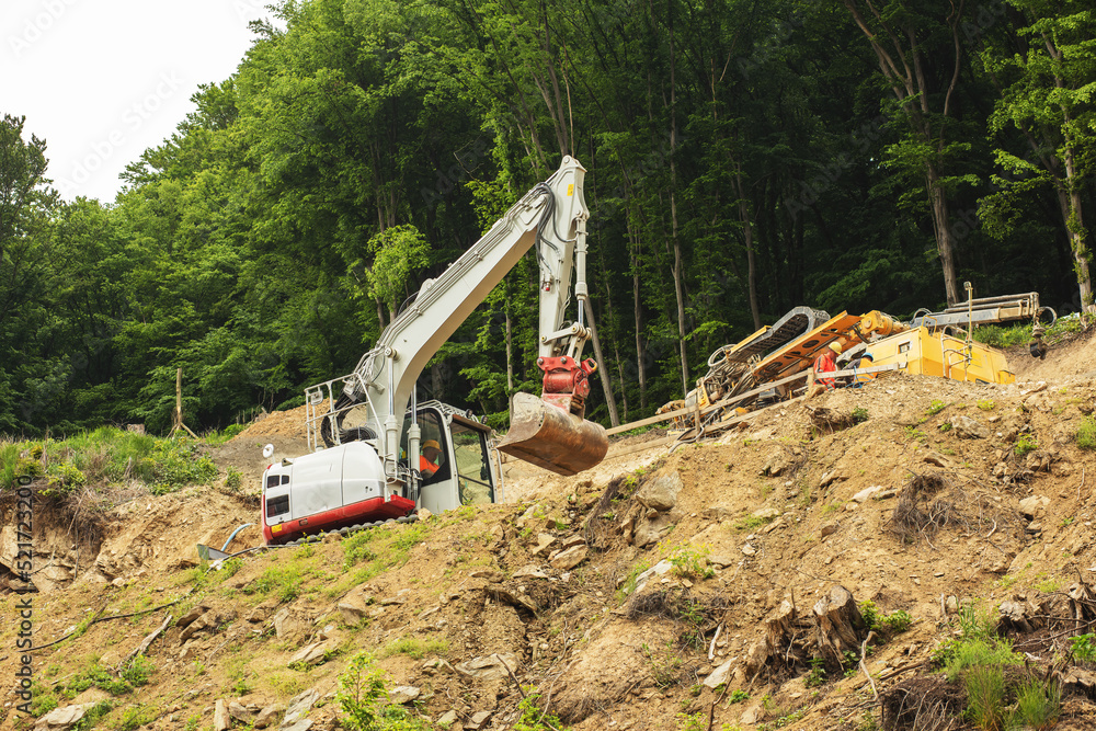 Excavator working on construction of higway on the steep slope of the hill. Excavator working on construction of higway on the steep slope of the hill.