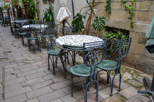 Vintage empty round tables and chairs on summer cafe terrace in the old city street 