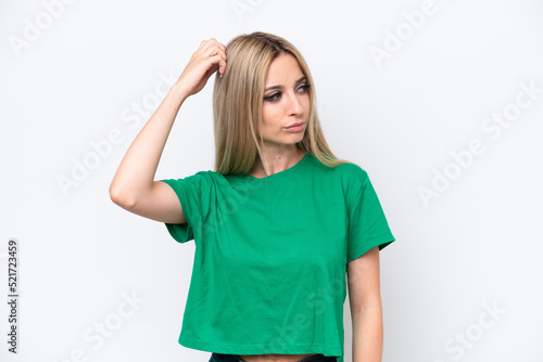 Pretty blonde woman isolated on white background having doubts while scratching head