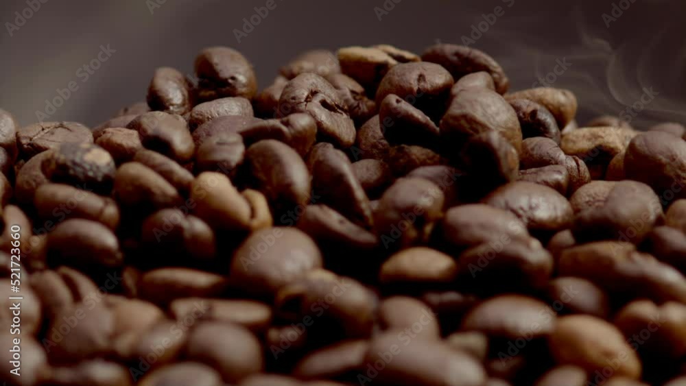 Aromatic steam lying coffee grains closeup. Smoke coming over roasted seeds. Aromatic steam lying coffee grains closeup. Smoke coming over roasted seeds.
