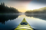 Kayak surfer on a misty lake by early morning in Quebec, Canada