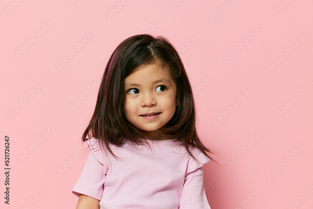 close horizontal portrait of a funny little girl pleasantly smiling standing on a pink background with empty space for inserting an advertising mockup close horizontal portrait of a funny little girl pleasantly smiling standing on a pink background with empty space for inserting an advertising mockup