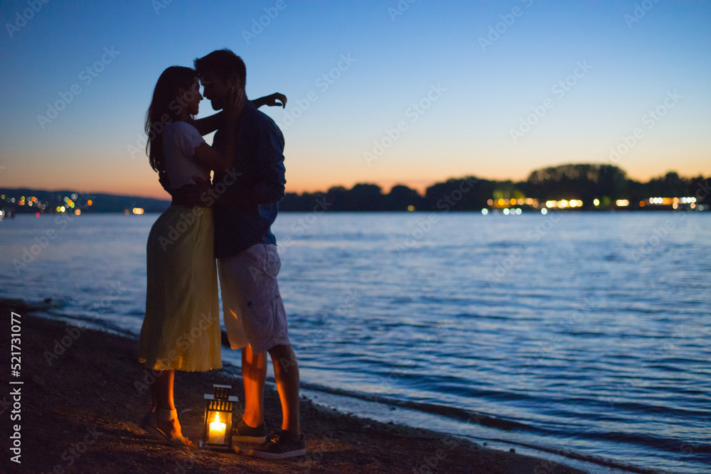 Silhouette of young couple in love hugging on the beach at summer ...