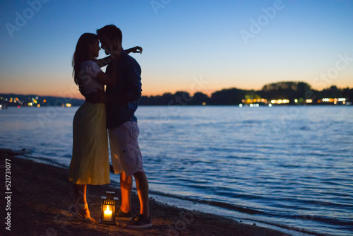 Silhouette of young couple in love hugging on the beach at summer sunset