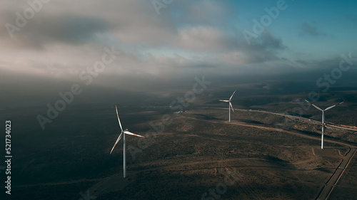 Wind turbines on beautiful sunny summer autumn mountain landsape. Curvy road through mountain Eolic park. Green ecological power energy generation. Wind farm eco field