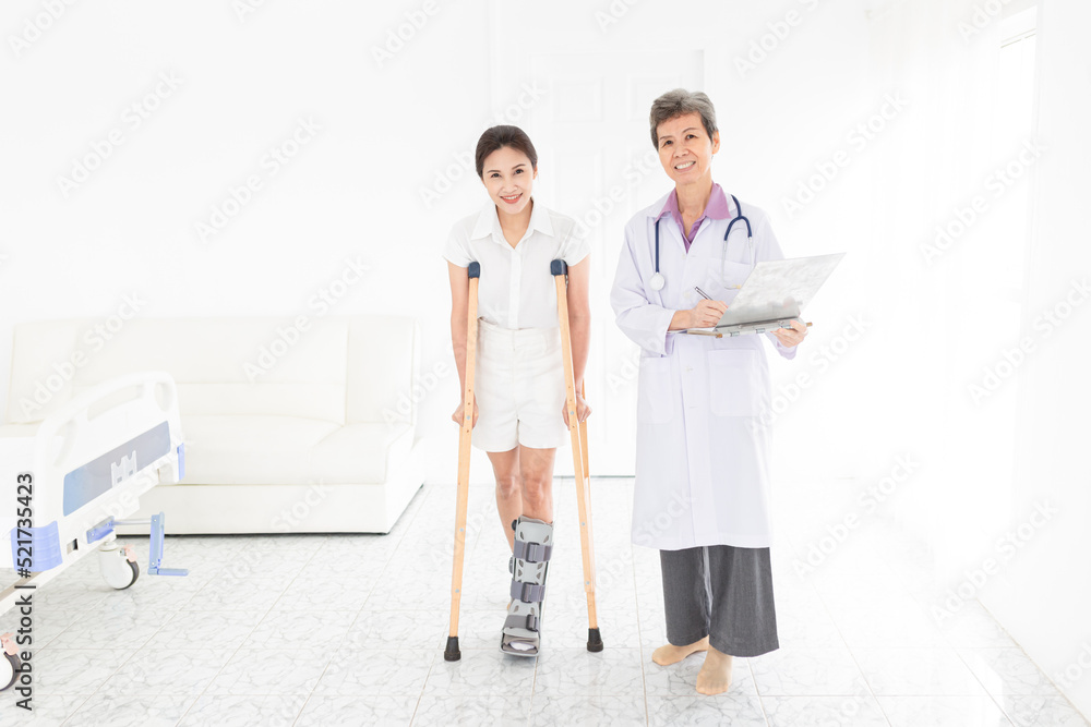 Obraz premium asian patient learning to use crutches with doctor, walk training and rehabilitation, doctor assessment of patient leg, patient wear air cast walking boot