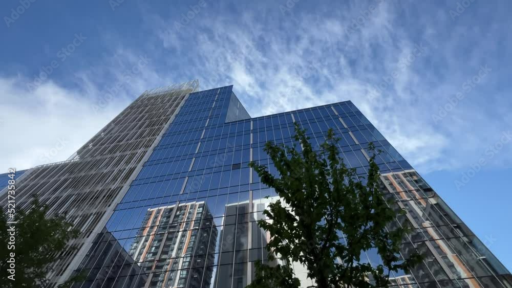 Bottom up view of the glassed office building exterior with blue sky reflection in the windows. Extreme wide angle shot Bottom up view of the glassed office building exterior with blue sky reflection in the windows. Extreme wide angle shot
