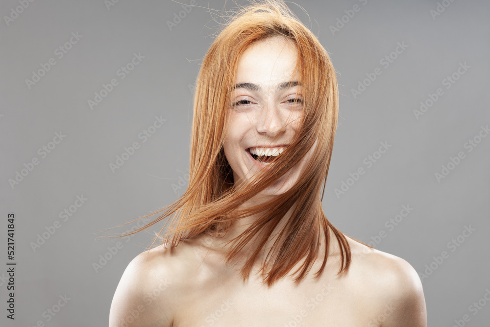 Beautiful dark burnt orange windy hair girl smiling. Studio portrait with happy face expression against gray background... Beautiful dark burnt orange windy hair girl smiling. Studio portrait with happy face expression against gray background...