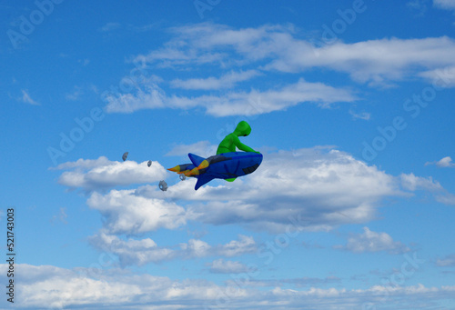 Green alien fancy kite on the blue cloudy sky.