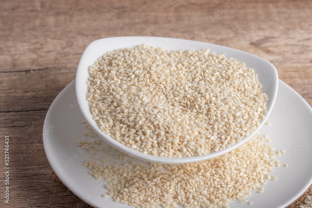 white sesame in white ceramic cup on wooden background white sesame in white ceramic cup on wooden background