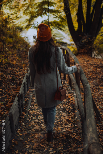 Young girl is walking alone in the wooden park in autumn season