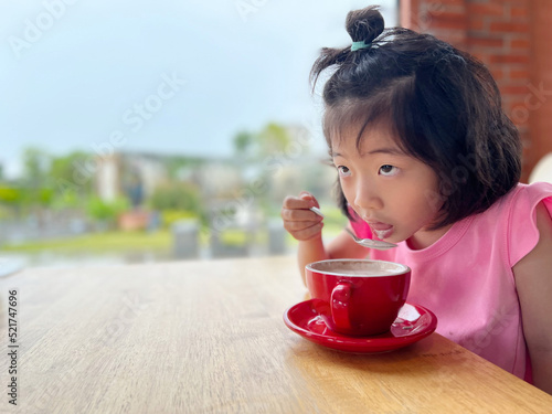 cute little beautiful girl slowly drinks hot chocolate milk with blank copy space