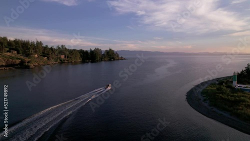Aerial footage motor boat at sunset, Whiffen Spit, Sooke Harbour, calm water, ocean, Vancouver Island. 5.4K TO 4K 24FPS photo