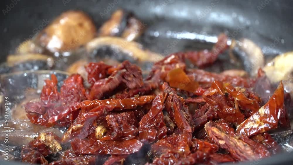 Frying chopped mushrooms champignon in a pan, adding sundried tomatoes