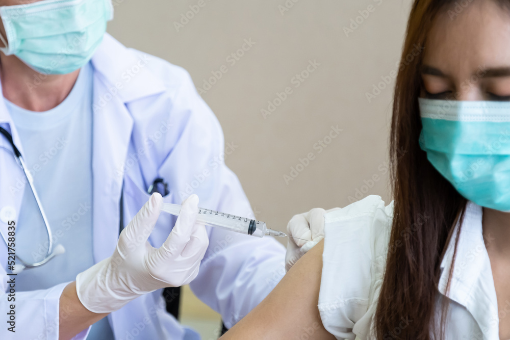 Selective focus at the syringe and needle that holding by female doctor who wearing surgical face mask. While prepare the medicine before inject to patient to create immunity to prevent illness. Selective focus at the syringe and needle that holding by female doctor who wearing surgical face mask. While prepare the medicine before inject to patient to create immunity to prevent illness.