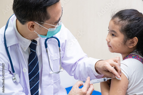 Young Asian girl get medical vaccination from the doctor with her mother sit and hold to support. Medical service for young people  kids. Immunity dose injection to prevent illness in children.