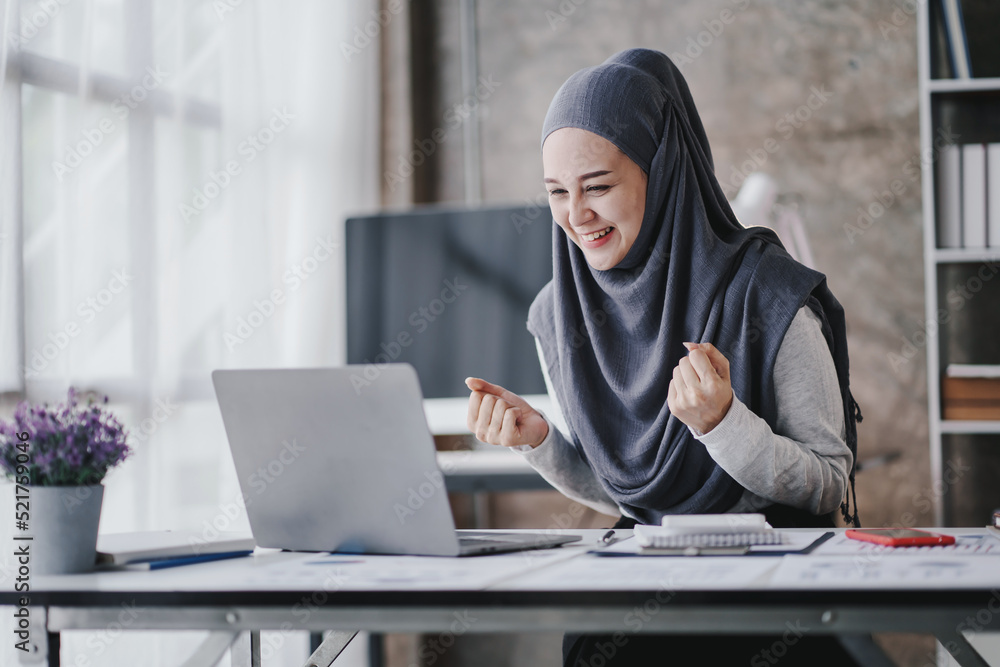 Muslim business women are very excited to close the sale. smiling arab woman taking notes and work on laptop