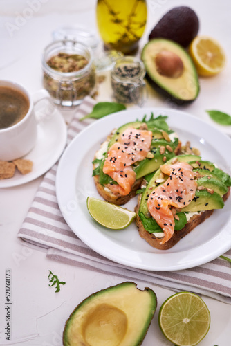 Freshly made Avocado, salmon and cream cheese toasts on a white ceramic plate