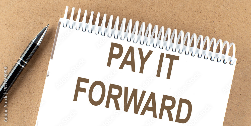PAY IT FORWARD text on a notepad with pen, business concept PAY IT FORWARD text on a notepad with pen, business concept