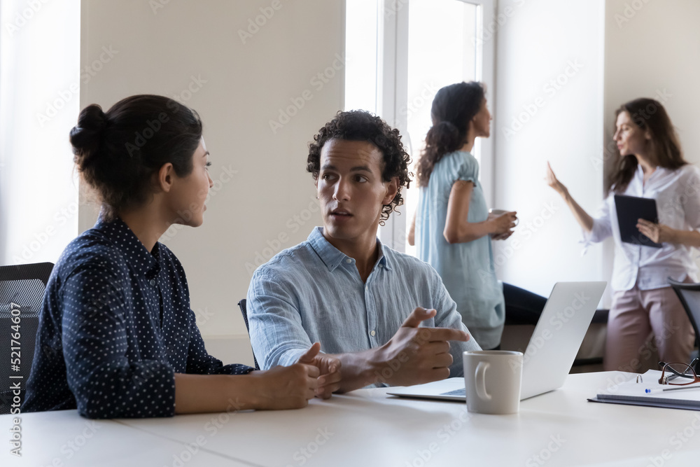 Multiethnic millennial co-workers, Indian woman and Hispanic man colleagues sit at desk discuss new project, work on collaborative task, share information, brainstorm creative ideas. Teamwork concept Multiethnic millennial co-workers, Indian woman and Hispanic man colleagues sit at desk discuss new project, work on collaborative task, share information, brainstorm creative ideas. Teamwork concept