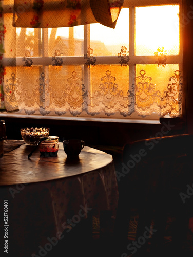 Dining room of veranda in summer house in sunset, country home of countryside in golden hour, cozy still life of rustic mood with light backlight from window and dark shadows of twilight