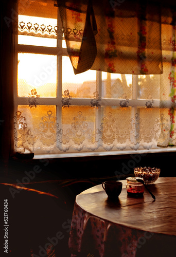 Dining room of veranda in summer house in sunset, country home of countryside in golden hour, cozy still life of rustic mood with light backlight from window and dark shadows of twilight