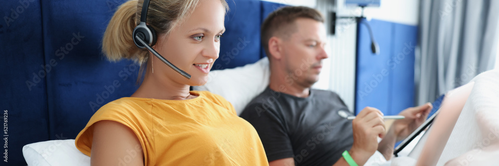 Fototapeta premium Woman with laptop and man with tablet in bed, freelancing