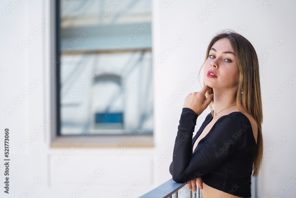 A woman on the railing of a white building, fashion portrait of a gorgeous young woman A woman on the railing of a white building, fashion portrait of a gorgeous young woman